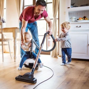 A man and two children cleaning the floor with a vacuum cleaner - Vacanti | Shattuck | Finocchiaro Attorneys