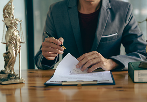 Close-up of Lady Justice statue on a lawyer's desk during a legal case review and signing.