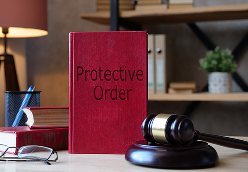 Red legal book titled 'Protective Order' with a judge's gavel for domestic violence legal help.